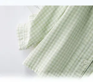 Detail of light green gingham pajama cuff with a white button on cotton fabric