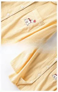 Details des gelb karierten Baumwollpyjamas mit Bärenstickerei und weißen Knöpfen