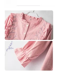 Detailed embroidery of daisies and ruffle trim on pink cotton pajama fabric surface