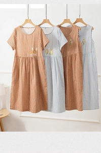 Detail of plaid cotton nightgowns in caramel and blue with floral bird embroidery