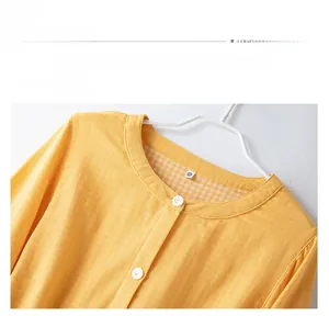 Detailed close-up of the round neckline on a yellow cotton pajama top with button closure