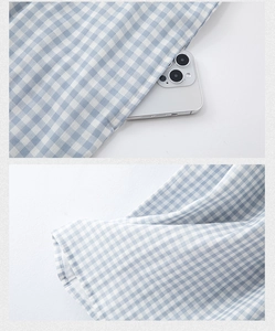 Detail showing deep side pocket on blue gingham cotton dress with a phone for scale