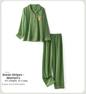 Close-up of green striped cotton pajamas with squirrel embroidery and yellow piping detail