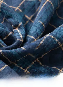 Close-up of blue quilted 100% cotton fabric with yellow grid pattern and soft texture