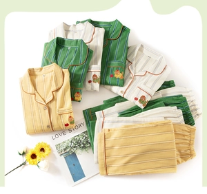 Close-up of three-color striped cotton pajamas featuring cat embroidery on a flat lay surface