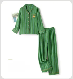Detail of green striped cotton pajamas featuring orange piping and a cat embroidery on the pocket