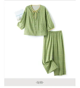 Detail of green plaid cotton pajamas set featuring drawstring bow and white buttons