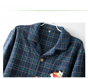 Detail view of quilted blue-green plaid pajama top featuring cute panda embroidery