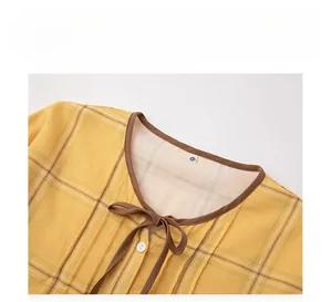 Detail of round neckline with brown trim and bow tie on yellow plaid cotton pajamas