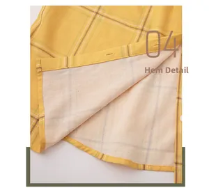 Detail of curved hemline on yellow plaid cotton pajamas with fine stitching and buttons