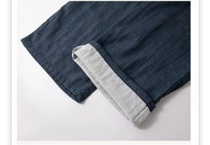 Détail du pantalon en coton bleu foncé avec ourlets retroussés et doublure grise contrastée