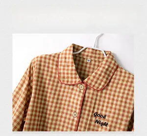 Detail des karamellfarbenen Gingham-Pyjama-Oberteils mit Good Night Stickerei und Paspel