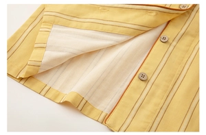Close-up of yellow cotton striped pajama set with natural wood buttons and fine stitching