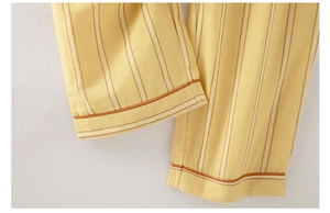 Detail of yellow cotton pajamas featuring fine vertical stripes and orange piping edges
