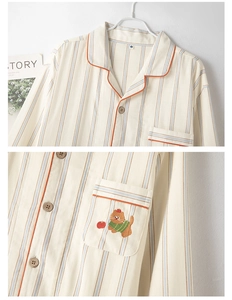 Detail of cotton striped pajama pocket featuring cat embroidery and wooden button