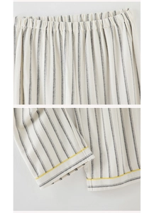 Detail of striped cotton pajama pants featuring elastic waist and yellow piping at the hem