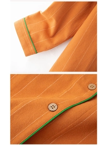 Detail of orange striped cotton pajama top featuring green piping and wooden buttons
