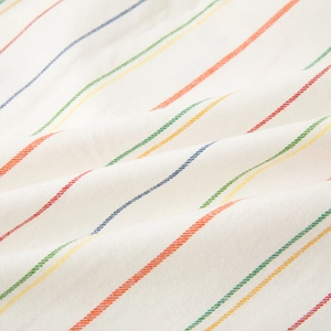 Pigiama in cotone a righe arcobaleno su fondo bianco crema con texture morbida e fine