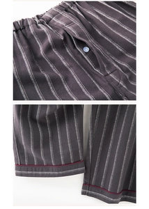 Detail of striped cotton pajama pants with elastic waist, button fly and red piping trim