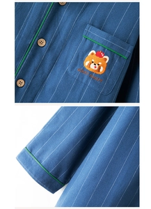 Close-up of blue striped cotton pajama top with panda embroidery and green piping detail