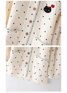 Close-up of quilted children's pajama with polka dots, wooden buttons, and cat embroidery