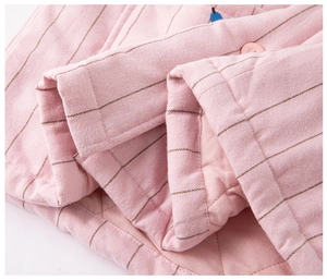 Detail of pink striped quilted fabric with diamond stitching and round button detail