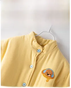 Détail de la veste thermique jaune pour enfants avec broderie chien et boutons bleus