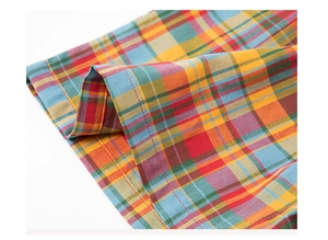 Detailed macro shot of red and yellow plaid cotton fabric with high-quality flat-felled seams