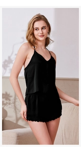 Détail d'un ensemble de nuit noir en satin avec caraco et short bordé de dentelle