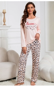 Dettaglio maglia pigiama rosa con stampa love e pantaloni leopardati in ambiente casa