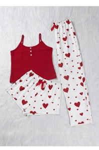 Détail à plat d'un caraco rouge en maille côtelée et pyjama à motif cœurs sur fond peluche