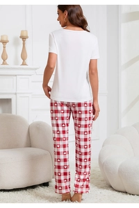 Set relax da donna con top bianco e pantaloni a quadretti rossi con cuori in un salotto
