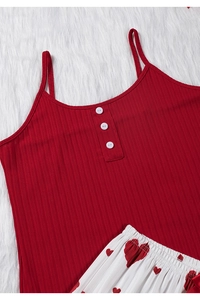 Détail du caraco rouge à boutons et du pantalon de pyjama à cœurs sur fourrure douce