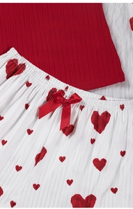 Détail du haut côtelé rouge et du pantalon blanc à cœurs rouges avec un nœud en satin