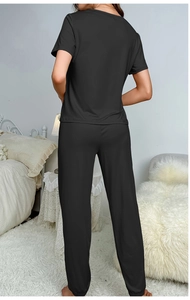 Back view of black short sleeve loungewear set with elastic cuffs in cozy bedroom