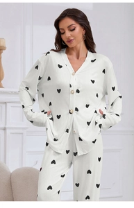 Detail of white rib-knit pajamas featuring black heart print and elegant pearl buttons