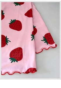 Dettaglio del tessuto rosa con stampa a fragola e bordo a coste rosso sulla camicia