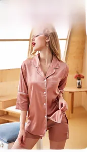 Detail of dusty pink satin pajama set featuring white piping and button-down front