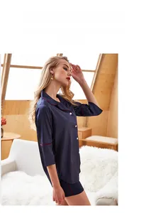 Detail of dark blue silk-like pajamas set with red trim and white buttons on short sleeves