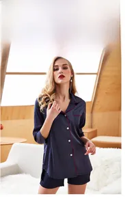 Detail of silk-like navy pajama set featuring contrast red piping and button-down shirt