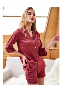 Detail view of burgundy satin pajama set featuring white buttons and navy blue piping