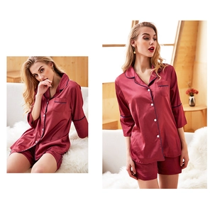 Detail of dark red silk pajamas with navy piping and pearl buttons in a home setting
