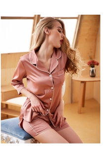Detail view of pink satin pajama set with elegant white piping and luxury texture