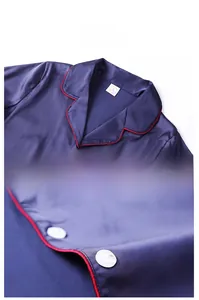 Detail of navy blue satin pajama top featuring red piping and white round buttons