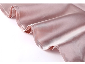 Detailaufnahme der glatten Satinoberfläche und des Saums am rosa Seidenbademantel