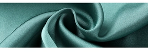 Gros plan du tissu satin de soie vert émeraude montrant une texture lisse et fluide