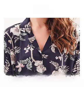 Nahaufnahme des V-Ausschnitts am dunkelblauen Seidenpyjama mit Blumen- und Vogelmotiven