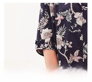 Detailaufnahme der marineblauen Seidenpyjama-Ärmel mit Blumenmuster und Schleifen