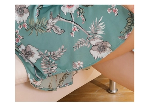 Detailed close-up of mint green floral satin robe fabric with bird and flower prints