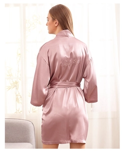 Detailed embroidery of Bride text on pink satin bridal robe with silk texture